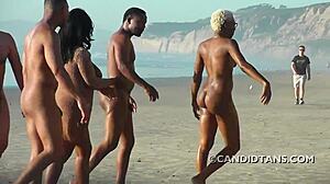Busty interracial par nyter nakenhet på stranden